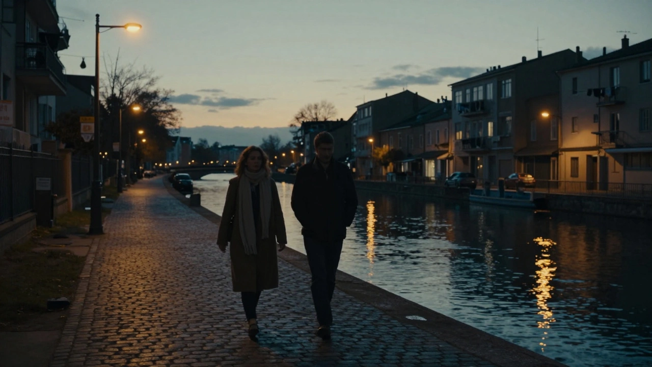 Two figures walking peacefully along a canal at dusk, reflections glimmering on the water.